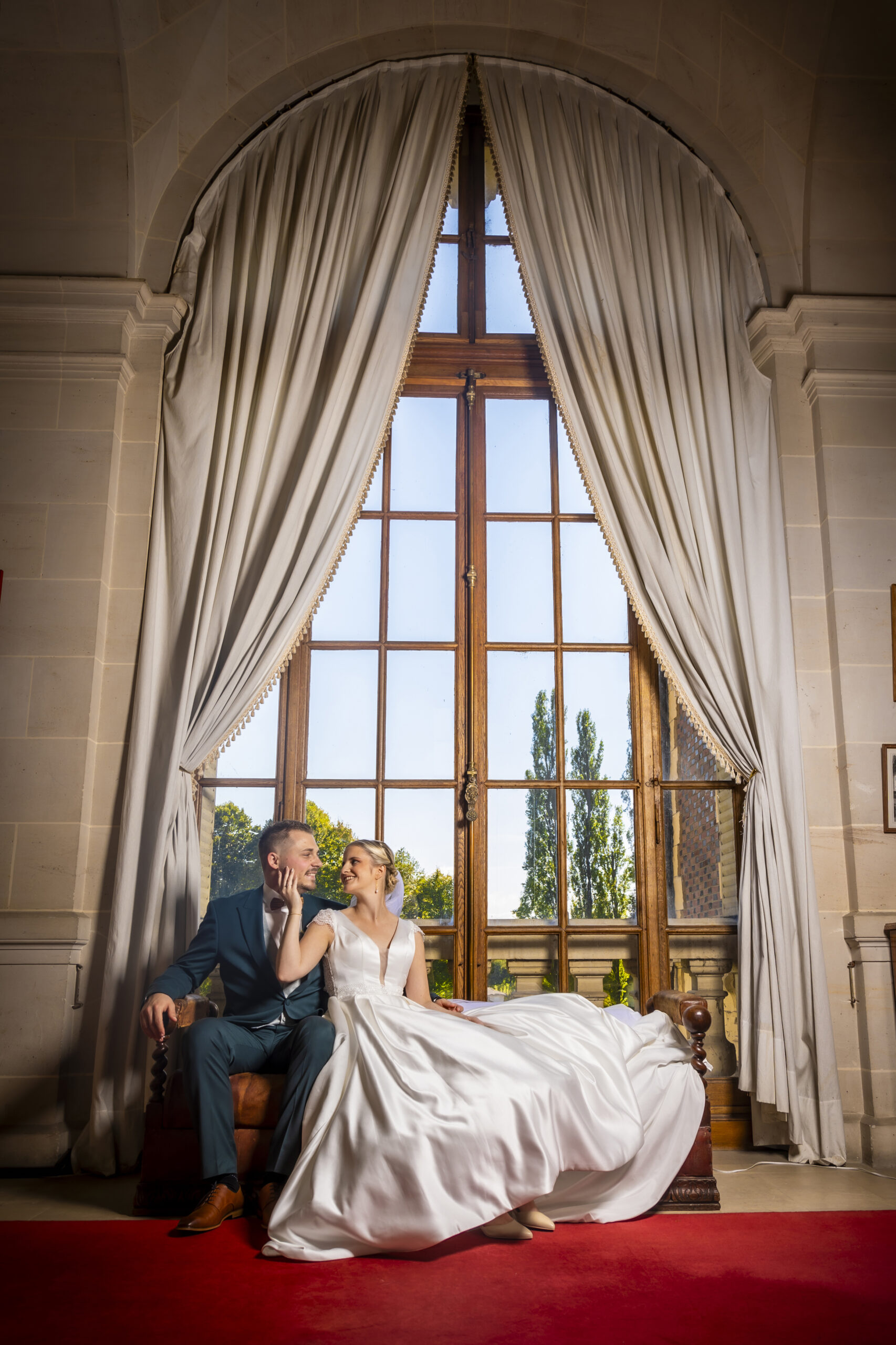 Mariée posant dans un escalier majestueux de château.